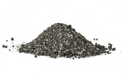 Un tas de granules noirs et gris d'amendement de sol TerraCottem, placé sur un fond blanc, montrant une texture granuleuse et irrégulière.